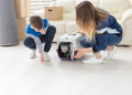 Slim young mother and little son launch their beautiful gray Scottish Fold cat into their new apartment in the living room. The concept of tradition with housewarming.